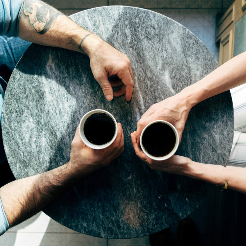 Två okända människor i möte med en kopp kaffe