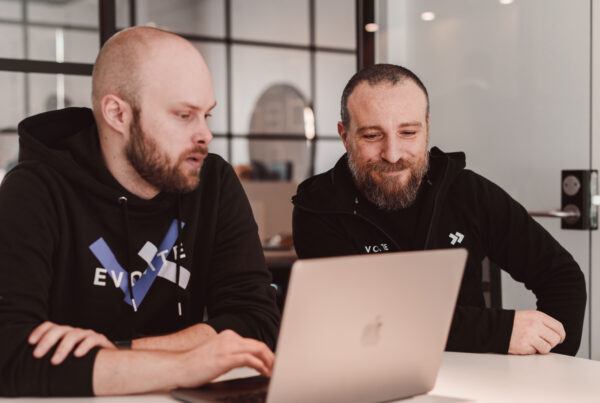Två anställda på Evolate som jobbar tillsammans framför en dator.